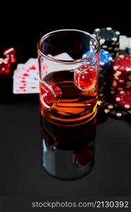 Casino chips, playing cards, glass of whiskey and dices on dark reflective background.. Casino chips, playing cards, glass of whiskey and dices on dark reflective background