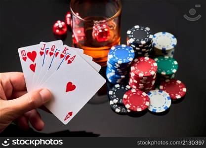 Casino chips, playing cards, glass of whiskey and dices on dark reflective background.. Casino chips, playing cards, glass of whiskey and dices on dark reflective background