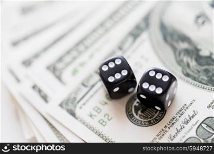 casino, gambling and fortune concept - close up of black dice and dollar cash money