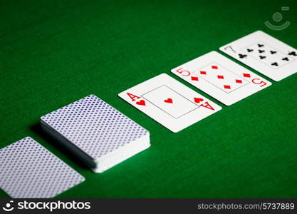 casino, gambling, poker, and entertainment concept - playing cards on green table surface