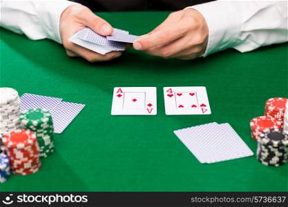 casino, gambling, poker, people and entertainment concept - close up of holdem dealer with playing cards and chips on green table