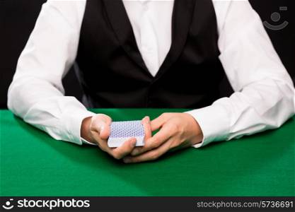 casino, gambling, poker, people and entertainment concept - close up of holdem dealer with playing cards