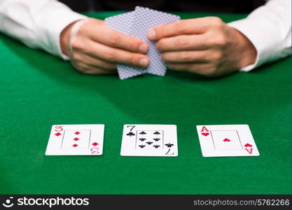 casino, gambling, poker, people and entertainment concept - close up of poker player holding playing cards at green casino table