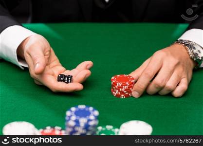 casino, gambling, poker, people and entertainment concept - close up of poker player with dice and chips at green casino table
