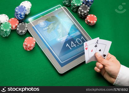 casino, online gambling, technology and people concept - close up of poker player with playing cards, tablet pc computer and chips at green casino table