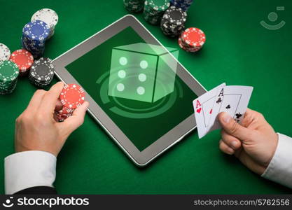 casino, online gambling, technology and people concept - close up of poker player with playing cards, tablet pc computer and chips at green casino table