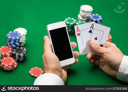 casino, online gambling, technology and people concept - close up of poker player with playing cards, smartphone and chips at green casino table