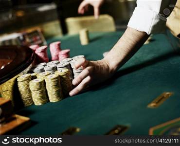 Casino worker&acute;s hand arranging gambling chips on a gambling table