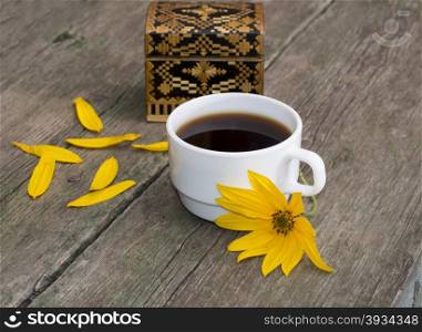 casket, petals, yellow flower and coffee, on a wooden table, a still life, a subject flowers and drinks
