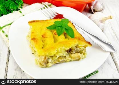 Casserole from mashed potatoes with a fish fillet in a plate on a towel against a light wooden board