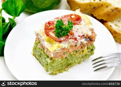 Casserole of salmon and rice with pesto, tomato and cheese in plate, bread, garlic and a jar of sauce on light wooden board background