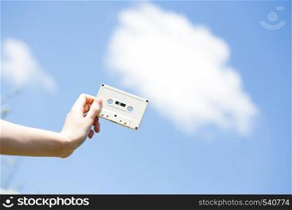 cassette in the hands of the girl against the blue sky. vintage mood