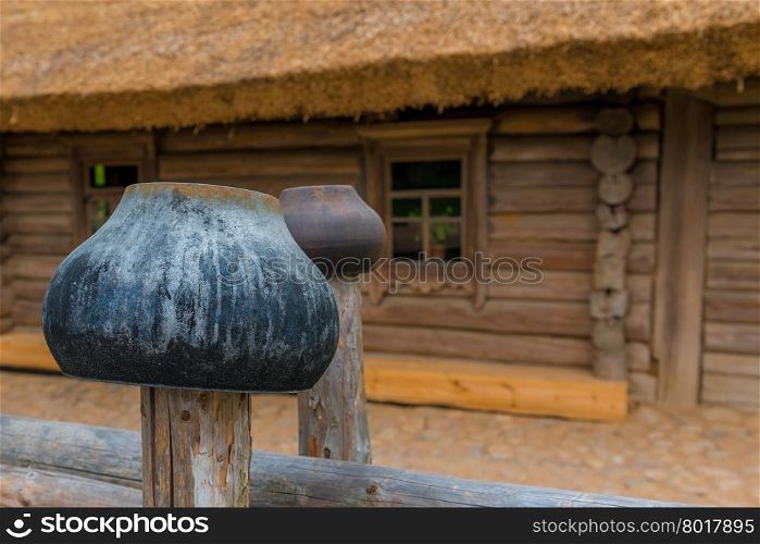 cast iron pots on a fence near a wooden farmhouse