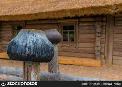 cast iron pots on a fence near a wooden farmhouse