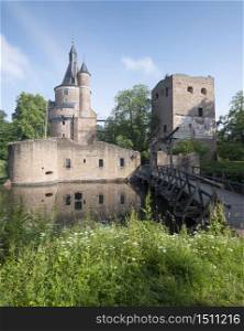 castle and ruin in dutch town of wijk bij duurstede in province of utrecht under blue sky and reflected in water of moat