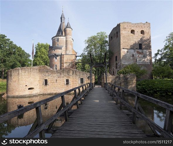castle and ruin in dutch town of wijk bij duurstede in province of utrecht under blue sky and reflected in water of moat