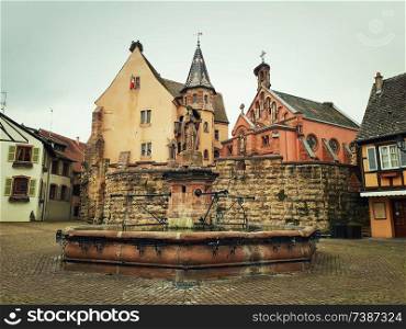 Castle, church and fountain named Saint Leon on the central square of Eguisheim village in Alsace, France.