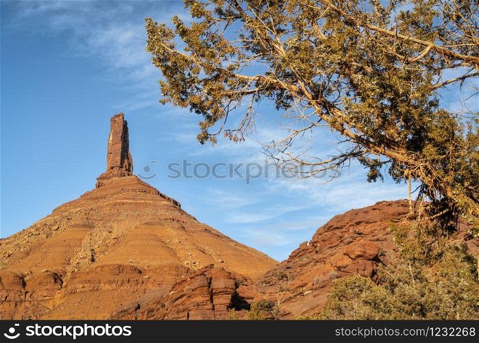 Castleton Tower framed by a juniper tree, iconic rock formation in Castle Valley near Moab, Utah. The Tower is world-renowned as a subject for photography and for its classic rock climbing routes.