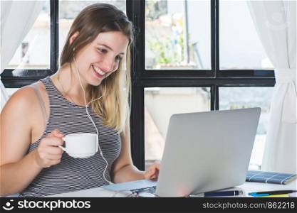 Casual beautiful woman with coffee cup working on laptop at home. Freelancer concept.