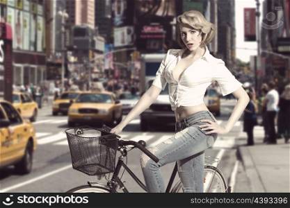 casual blonde girl with casual style wearing jeans and shirt in sensual pose near bicycle