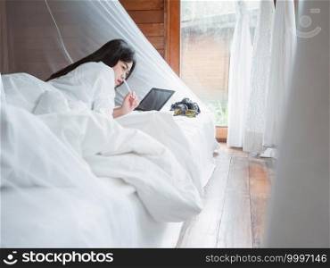 casual business concept from woman working with the tablet at bedroom on the bed.