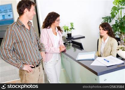 Casual business team working together at office reception, looking at documents, talking.