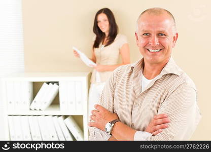 Casual businessman attractive smiling crossed arms businesswoman in background