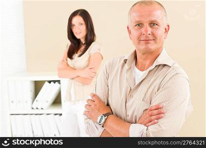 Casual businessman attractive smiling crossed arms businesswoman in background