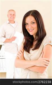 Casual businesswoman attractive smiling crossed arms businessman in background