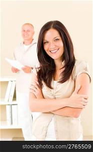 Casual businesswoman attractive smiling crossed arms businessman in background