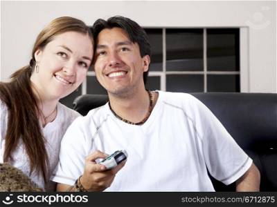 casual couple smiling at home while watching television