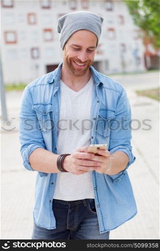 Casual fashion guy taking a walk with his mobile in the city