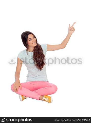 Casual girl sitting on the floor pointing something isolated on white background