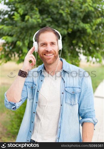 Casual guy with a denim clothes in a park listening music with his mobile