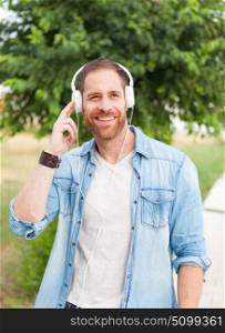 Casual guy with a denim clothes in a park listening music with his mobile