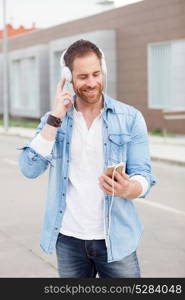 Casual guy with a denim clothes in the street listening music with his mobile