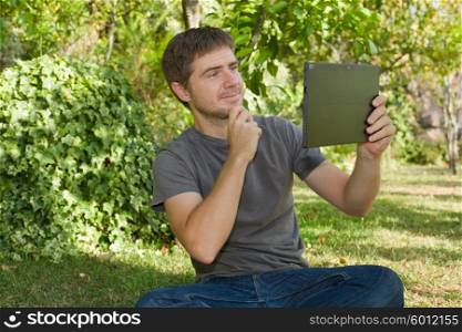 casual man taking a picture with a tablet pc, outdoor