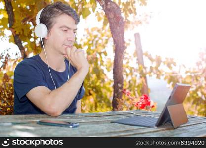 casual man working with a tablet pc, with headphones, outdoor
