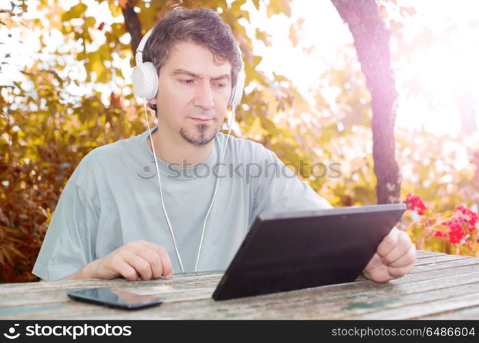 casual man working with a tablet pc, with headphones, outdoor. working