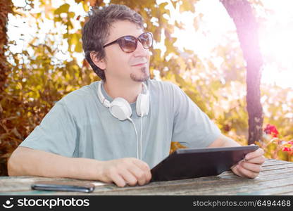 casual man working with a tablet pc, with headphones, outdoor. working