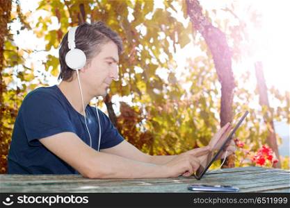 casual man working with a tablet pc, with headphones, outdoor. working