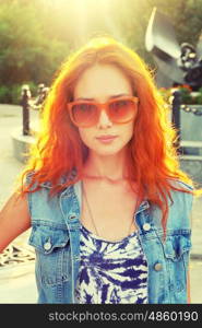 Casual red haired girl front view. Street fashion women in orange sunglasses backlit.