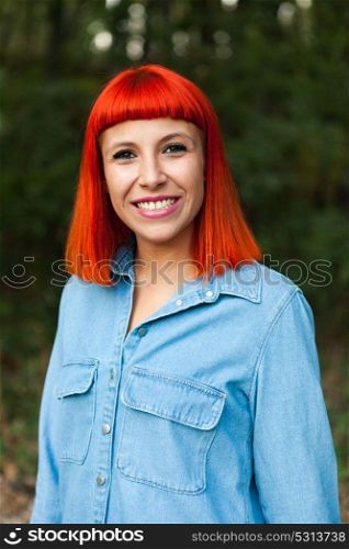 Casual redhead girl with denim shirt in the forest looking at camera