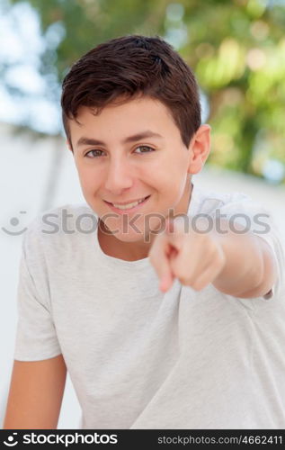 Casual teenager boy indicating at camera outdoor