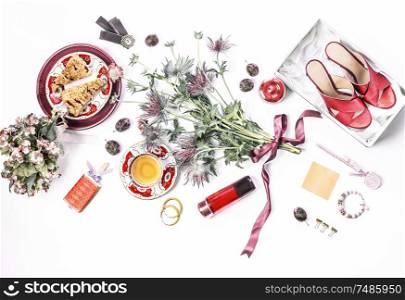 Casual woman beauty blog flat lay composition. Red high heels in box, cosmetics, perfume, flowers bunch, cakes cup of tea and bijou on white desk background. Top view. Fashion blogging template