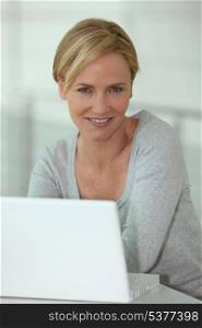 Casual woman using a white laptop computer in a white room