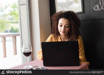 Casual woman using laptop at coffee shop