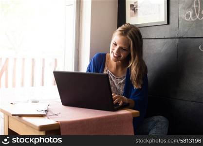 Casual woman using laptop at coffee shop