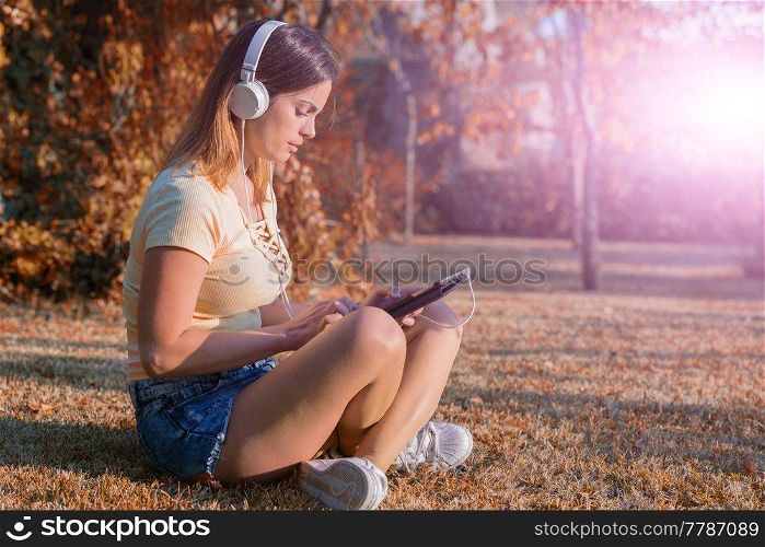 casual woman working with a tablet pc, with headphones, outdoor
