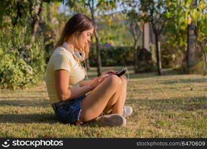 casual woman working with a tablet pc, with headphones, outdoor. woman with tablet